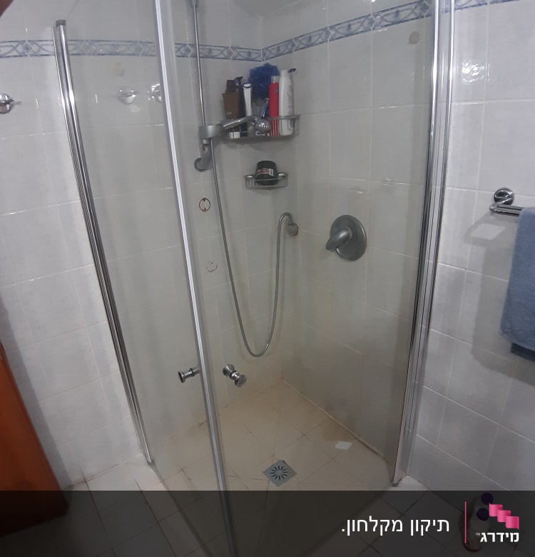 מקלחון זכוכית עם מדף מוצרים ומקלחת יד